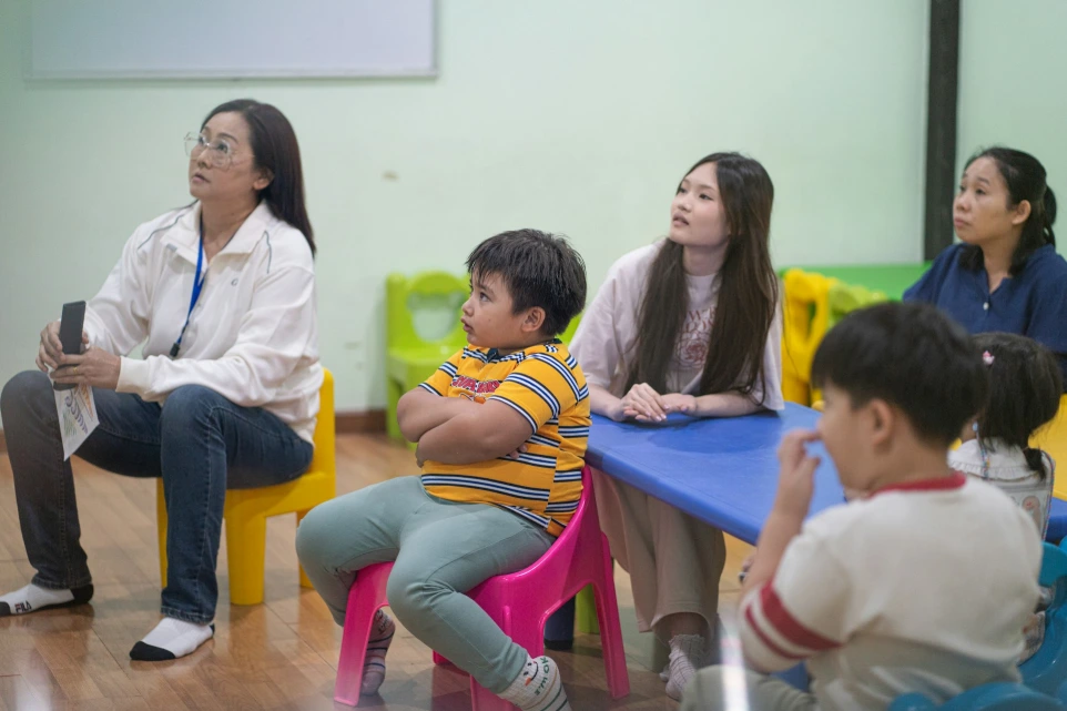 Adults and children sitting in a classroom setting